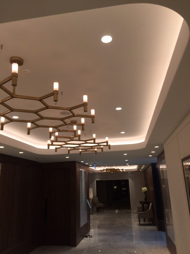 Modern commercial office space with architectural ceiling contour recessed linear LED lighting creating clean geometric light patterns