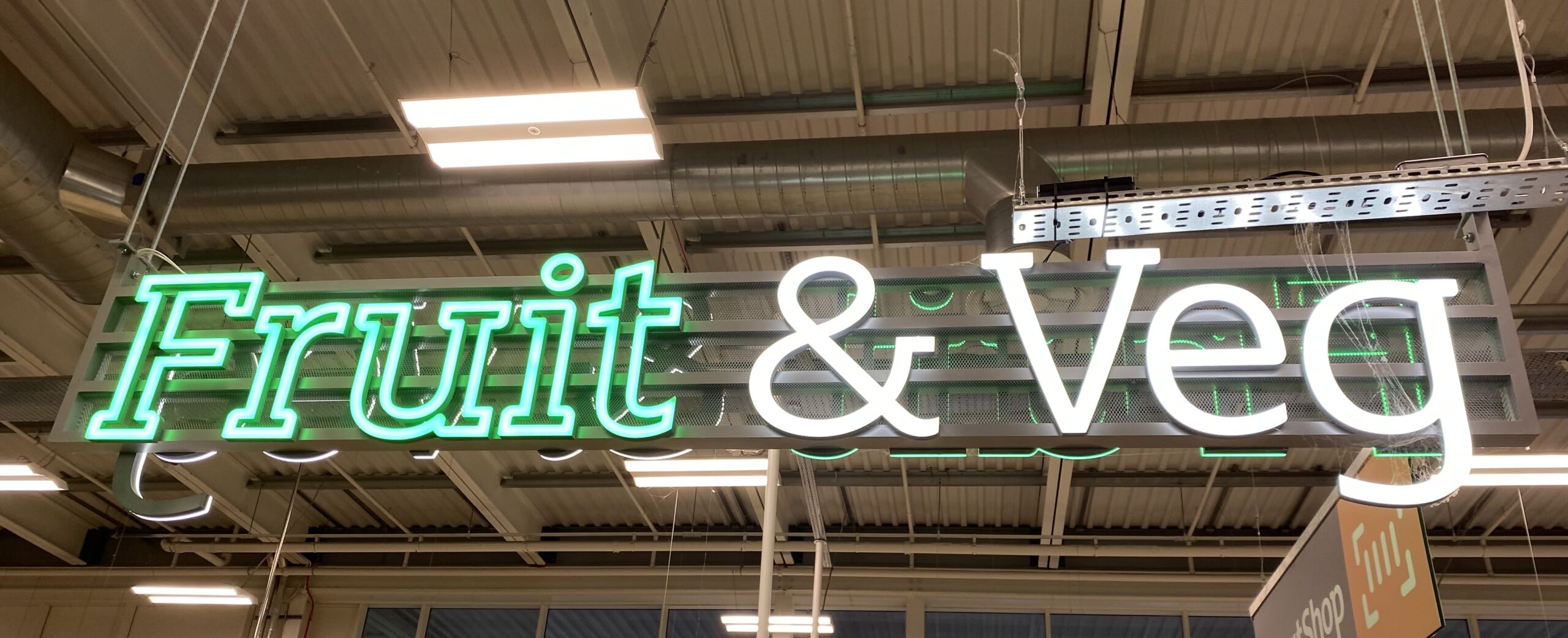 Large-scale illuminated interior storefront signage installed at a Manchester retail park
