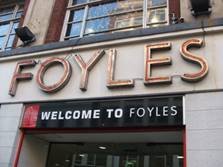 Professional sign installers fitting custom external shop front signage on a London high street